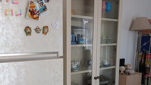 Eine Küche mit einem weißen Kühlschrank, einem Schrank mit Glastüren und einer Lampe.