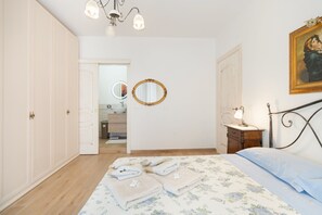 A bedroom with a bed, a nightstand, a mirror, and a door leading to a bathroom. - 'Casa Venere' Apartment with Balcony and Air Conditioning (Pachino)