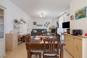 Ein gut beleuchtetes Wohnzimmer mit einer Couch, einem Esstisch und einer Küchenzeile.