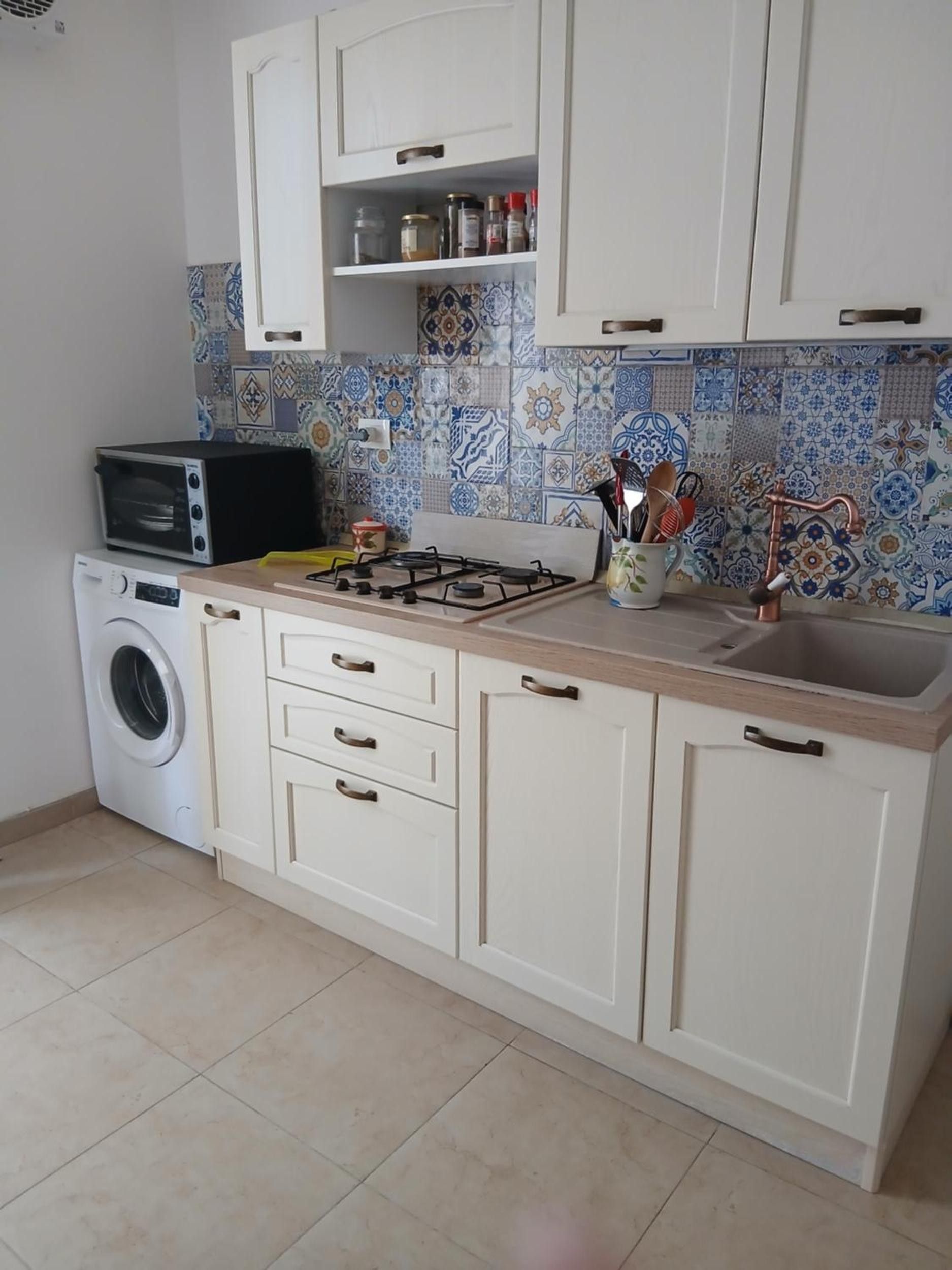 Une cuisine équipée d’un lave-linge, d’une cuisinière et d’un évier.