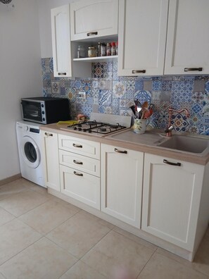Une cuisine équipée d’un lave-linge, d’une cuisinière et d’un évier.