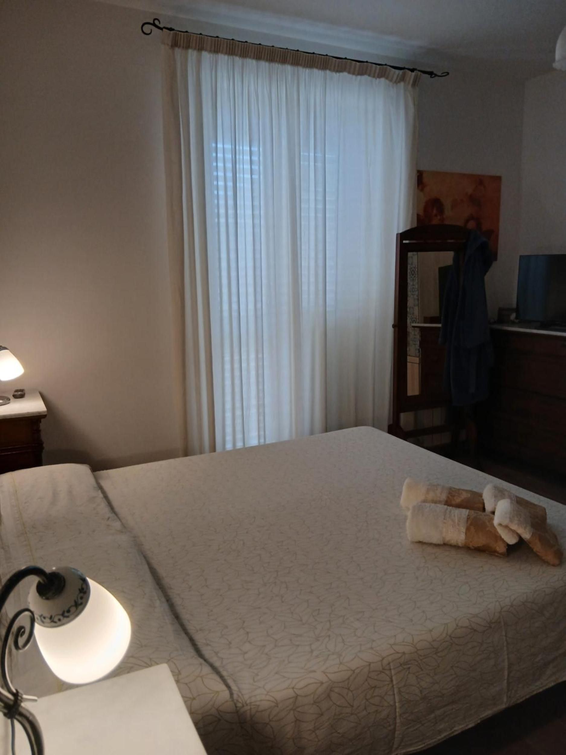 Una camera d'albergo con un letto, una scrivania con una lampada, uno specchio e un televisore.