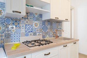Eine Küche mit Gasherd, Spüle und einer Spritzschutzwand mit blau-weißen Fliesen.