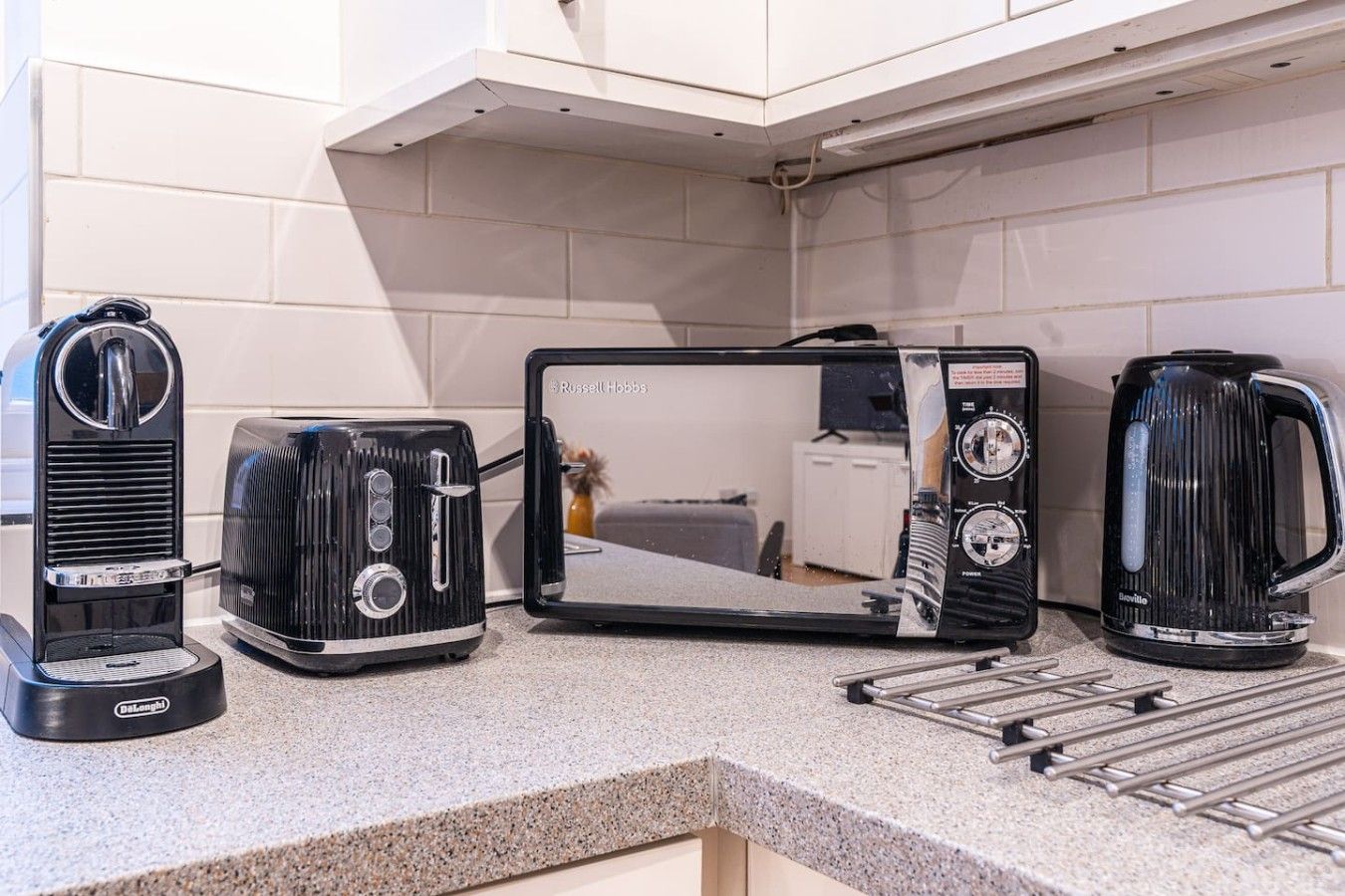 Cozinha com cafeteira, torradeira e chaleira sobre a bancada.