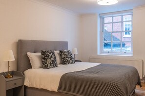 A bedroom with a bed, two bedside lamps, a window, and a radiator. - Historic City of London Gem | 1 Min to Cannon St (Greater London)