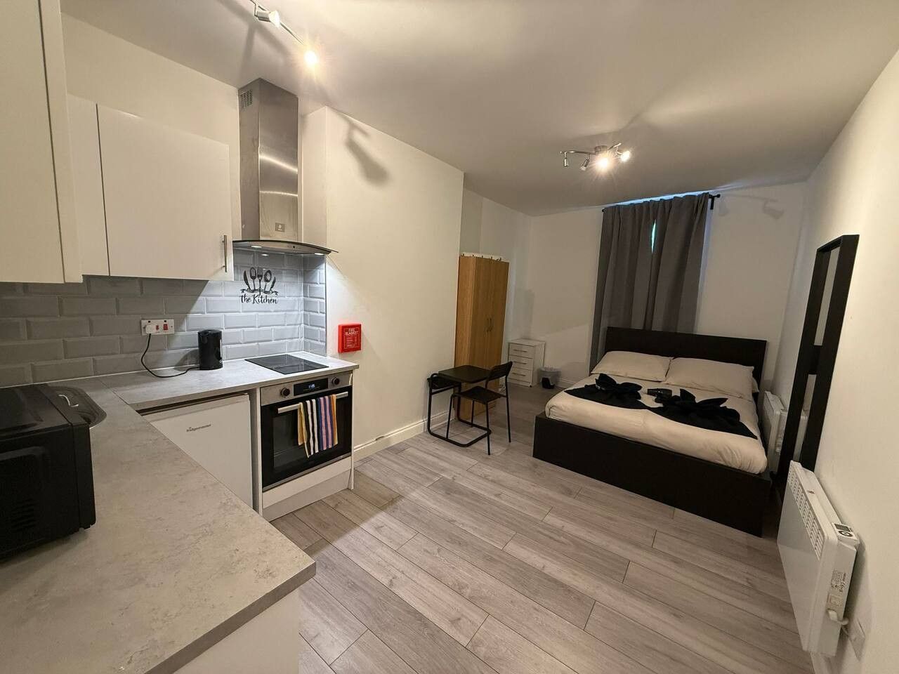Une chambre compacte comprenant un lit, une petite kitchenette et une salle de bain.