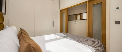 A bedroom with a bed, a wardrobe, and a door leading to a bathroom.