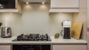 A modern kitchen with a gas stove, a coffee machine, and a toaster.