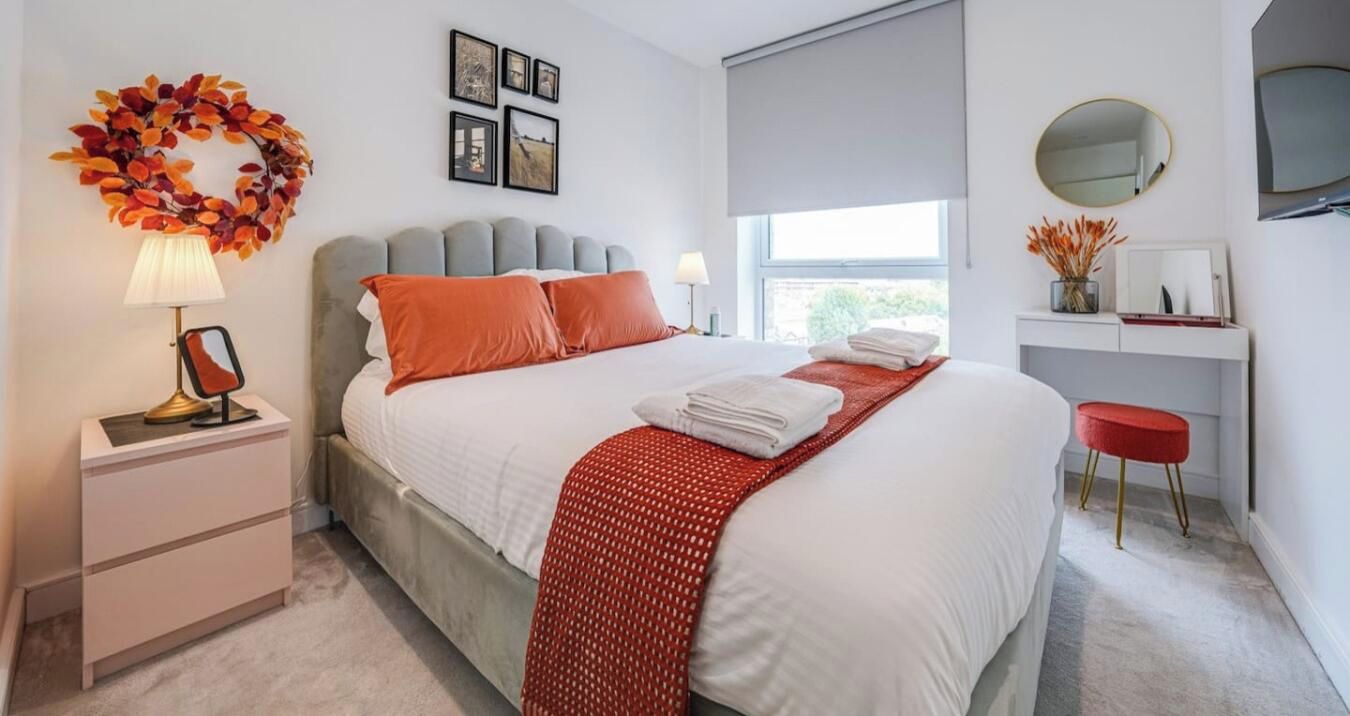 Een moderne slaapkamer met een bed, nachtkastjes, een spiegel, een raam en een wanddecoratie.