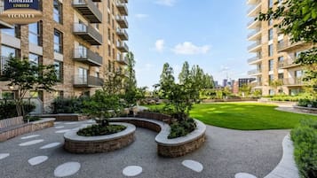 A modern apartment complex with multiple balconies, landscaped gardens, and a clear sky.