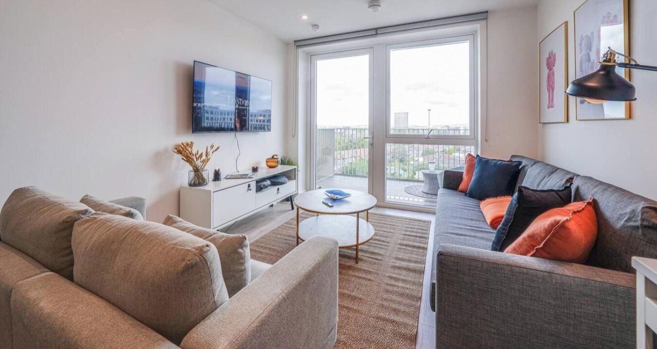 A modern living room with a sofa, a coffee table, and a TV mounted on the wall.