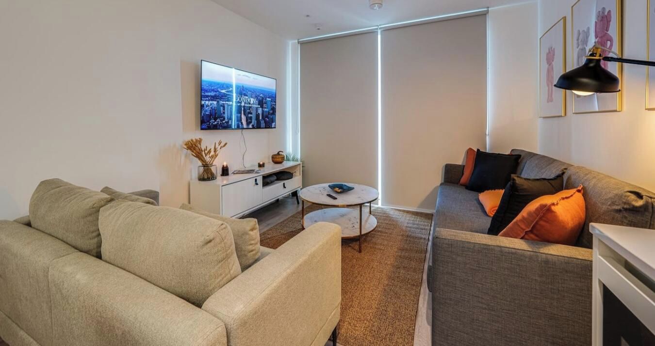 Een moderne woonkamer met een bank, een salontafel en een aan de muur bevestigde televisie.