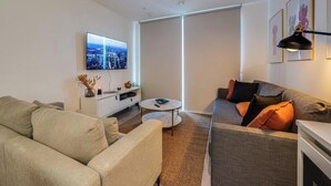 Ein modernes Wohnzimmer mit einer Couch, einem Couchtisch und einem an der Wand befestigten Fernseher.