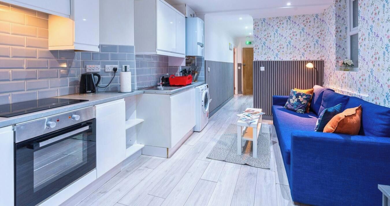 A modern kitchen with a built-in oven, a coffee machine, and a red storage basket.