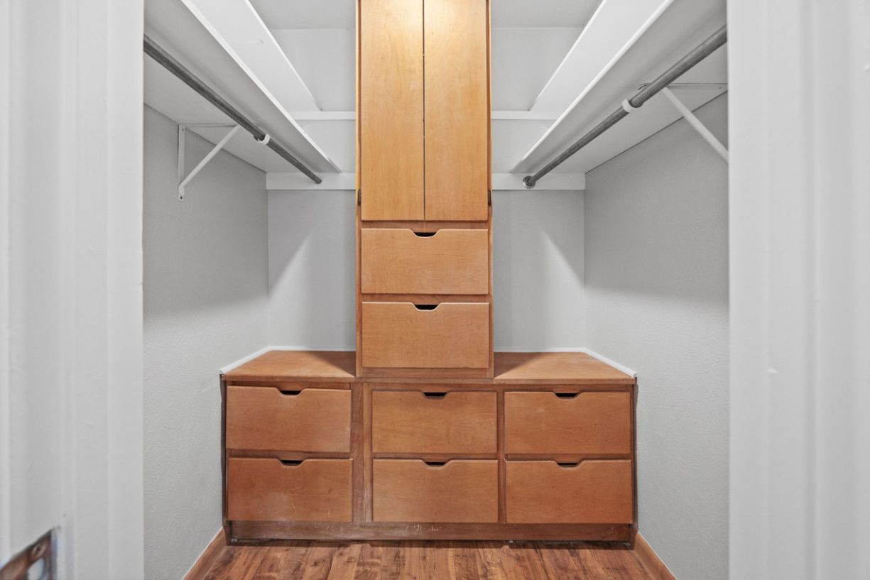 Un dressing avec un grand placard en bois au centre et de nombreux tiroirs.
