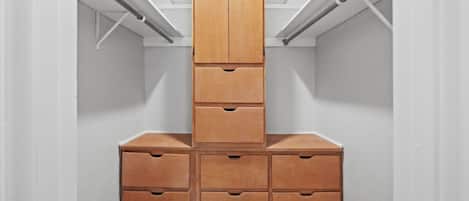 A walk-in closet with a central wooden cabinet and multiple drawers.
