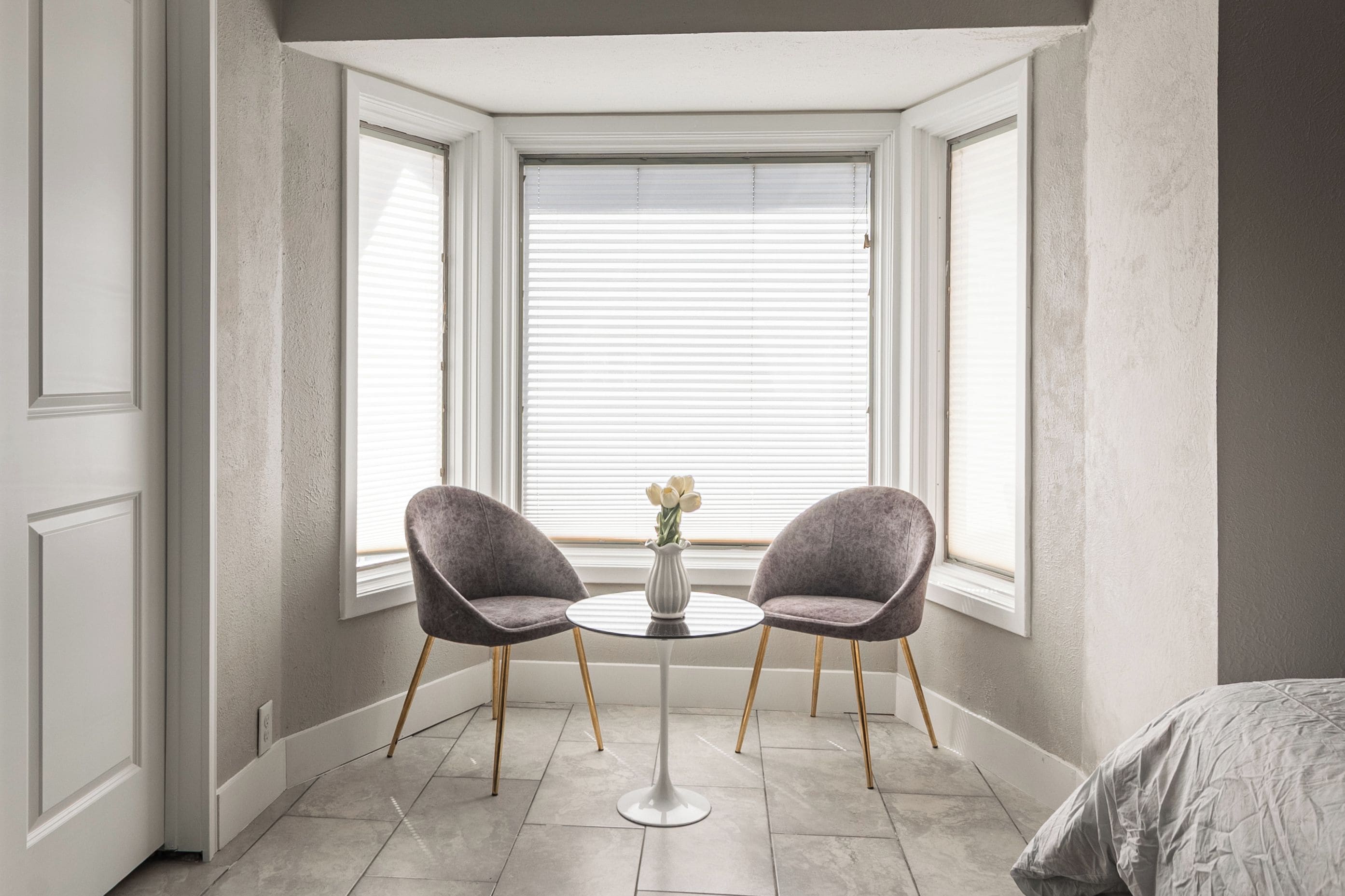 A room with two chairs, a small table, and a window with blinds.
