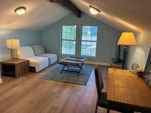 A loft-style room with a sloped ceiling, a sofa, a dining table, and a window with a view. - Luxury SoCo Oasis, Private Pool, Large Covered Patio & Shuffleboard (Austin)