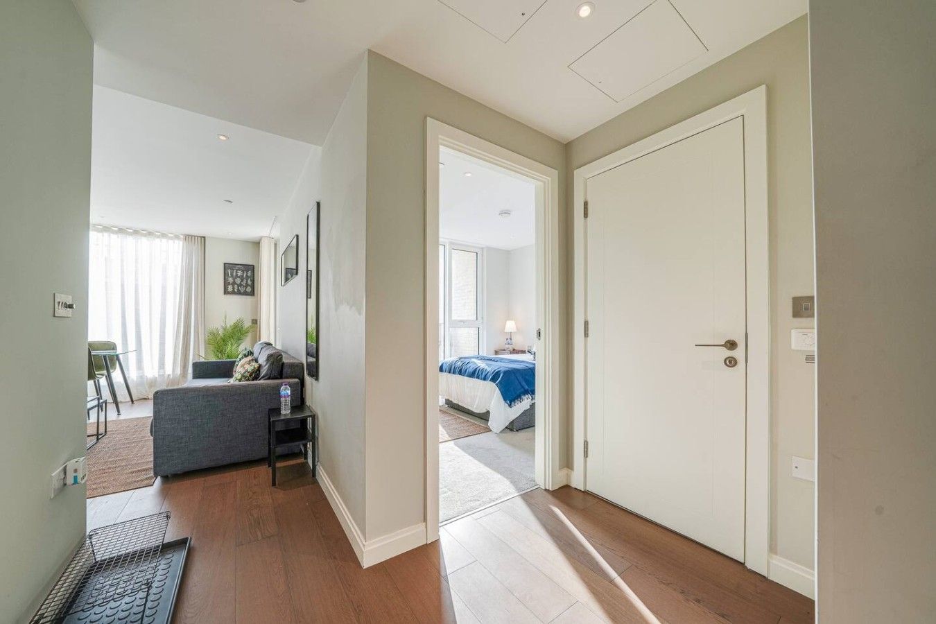 A modern interior with a living area, a bedroom with a bed, and a hallway leading to another room.