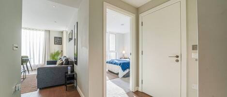 A modern interior with a living area, a bedroom with a bed, and a hallway leading to another room.