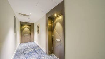 A hallway with two doors, a marble-patterned floor, and a vent on the left wall.
