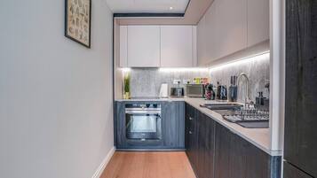 A modern kitchen with a built-in oven, a sink, and a countertop with various appliances.