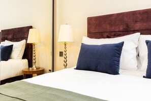Ein Hotelzimmer mit einem großen Bett, zwei Nachttischen, Lampen und einem Spiegel.