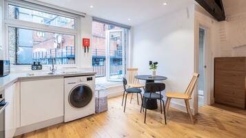 A compact kitchen with a washing machine, a sink, and a dining area with chairs and a table.
