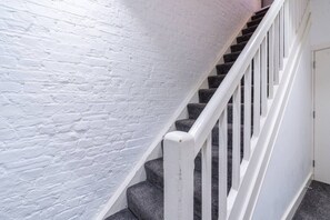 A staircase with white railings and dark steps, leading to a door.