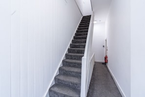 A staircase with carpeted steps and white walls, leading to a landing. - Farringdon Entire Building | 4BR | Sleeps 18 (Greater London)