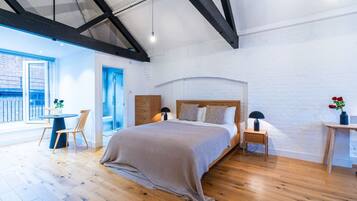A modern bedroom with a wooden bed, a small bedside table, a chair, and a view of the outside.