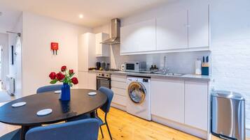 A compact kitchen with a washing machine, a microwave, and a sink.