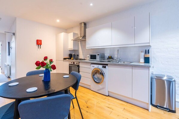 A compact kitchen with a washing machine, a microwave, and a sink.