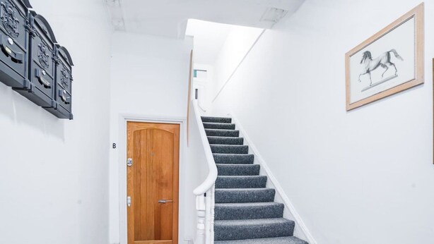 Eine Treppe mit einer Holztür am unteren Ende und einem gerahmten Bild an der Wand.