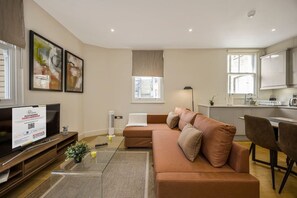 A modern living room with a sofa, a TV, and a dining area. - Fitzrovia 1BR Retreat | Near Soho & Tube-9 (Greater London)