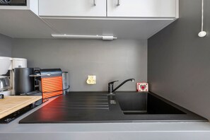 Een moderne keuken met een zwart aanrecht, een spoelbak en een koffieapparaat.