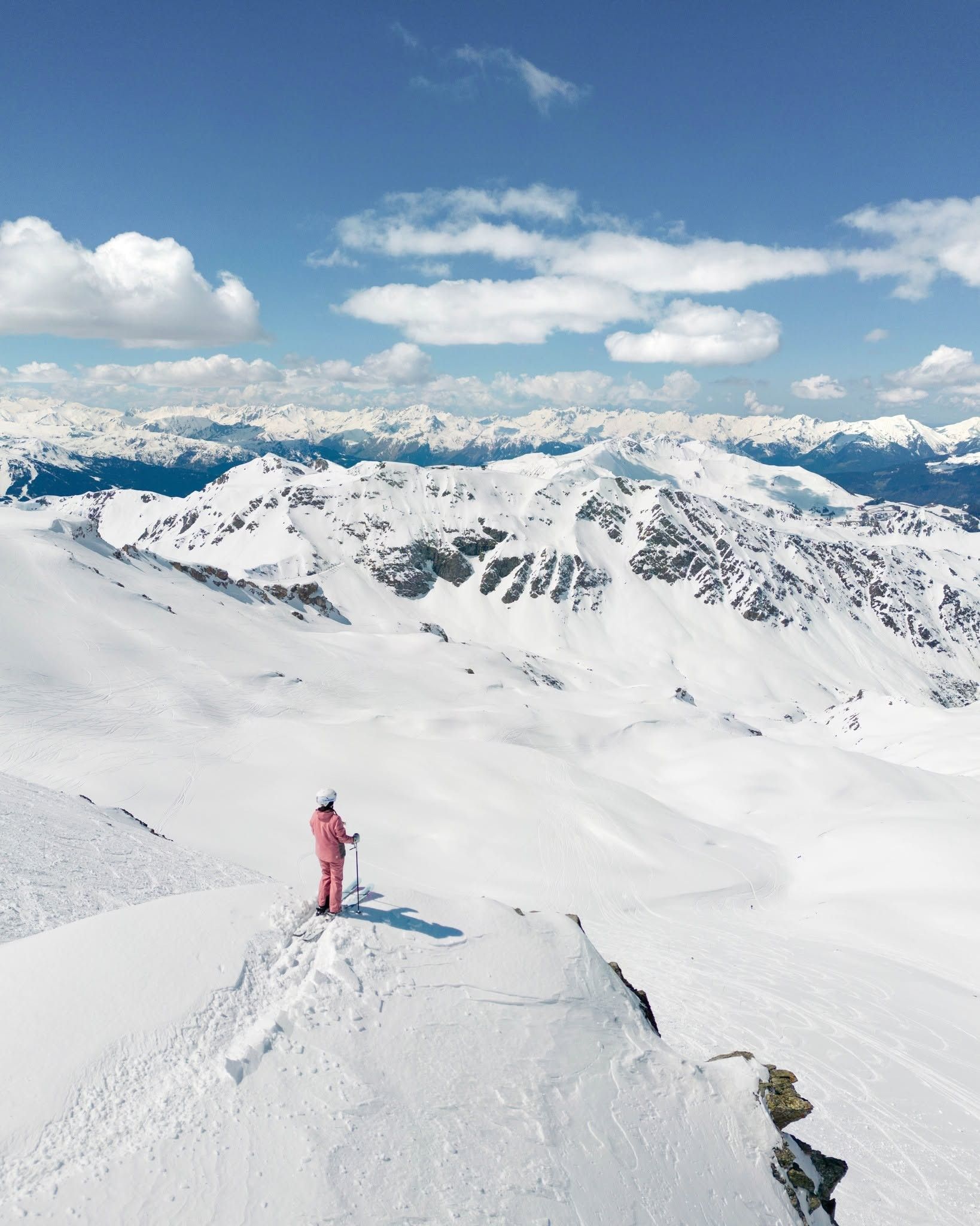 A snow-covered mountain landscape with a person standing on a snow-covered ridge.