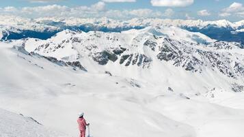 A snow-covered mountain landscape with a person standing on a snow-covered ridge.
