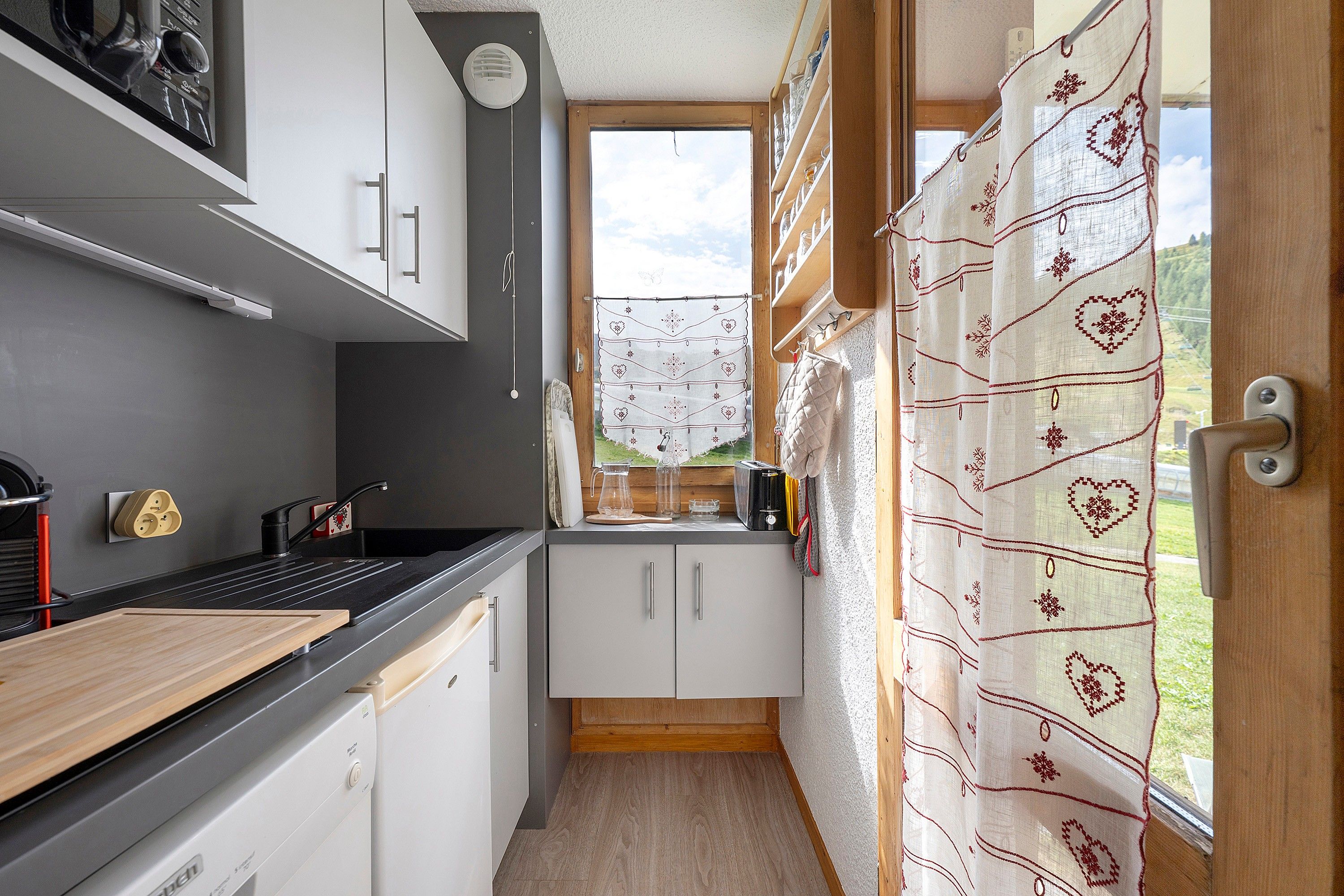 A compact kitchen with a window, a toaster, and a sink.