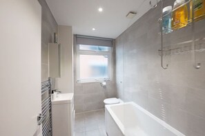 Un baño moderno con bañera, inodoro y ventana.