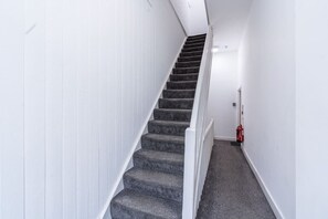 Una escalera con peldaños alfombrados y paredes blancas, que conduce a una plataforma.