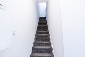 A staircase with a white wall on one side and a window at the top. - Farringdon 1BR | Sleeps 4 | Elizabeth Line Direct (Greater London)