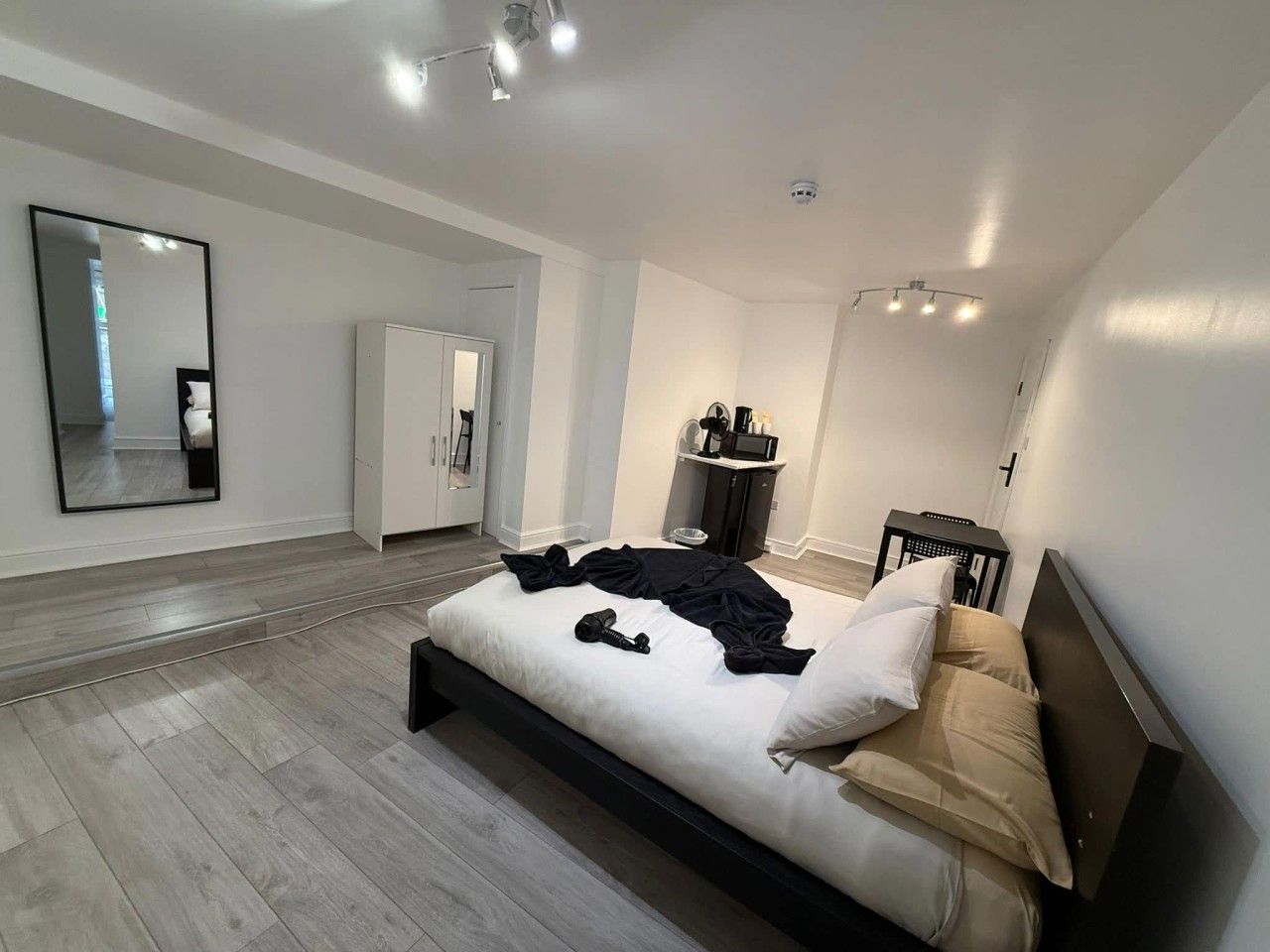 Una camera da letto moderna con un letto grande, un armadio, uno specchio e un angolo studio.