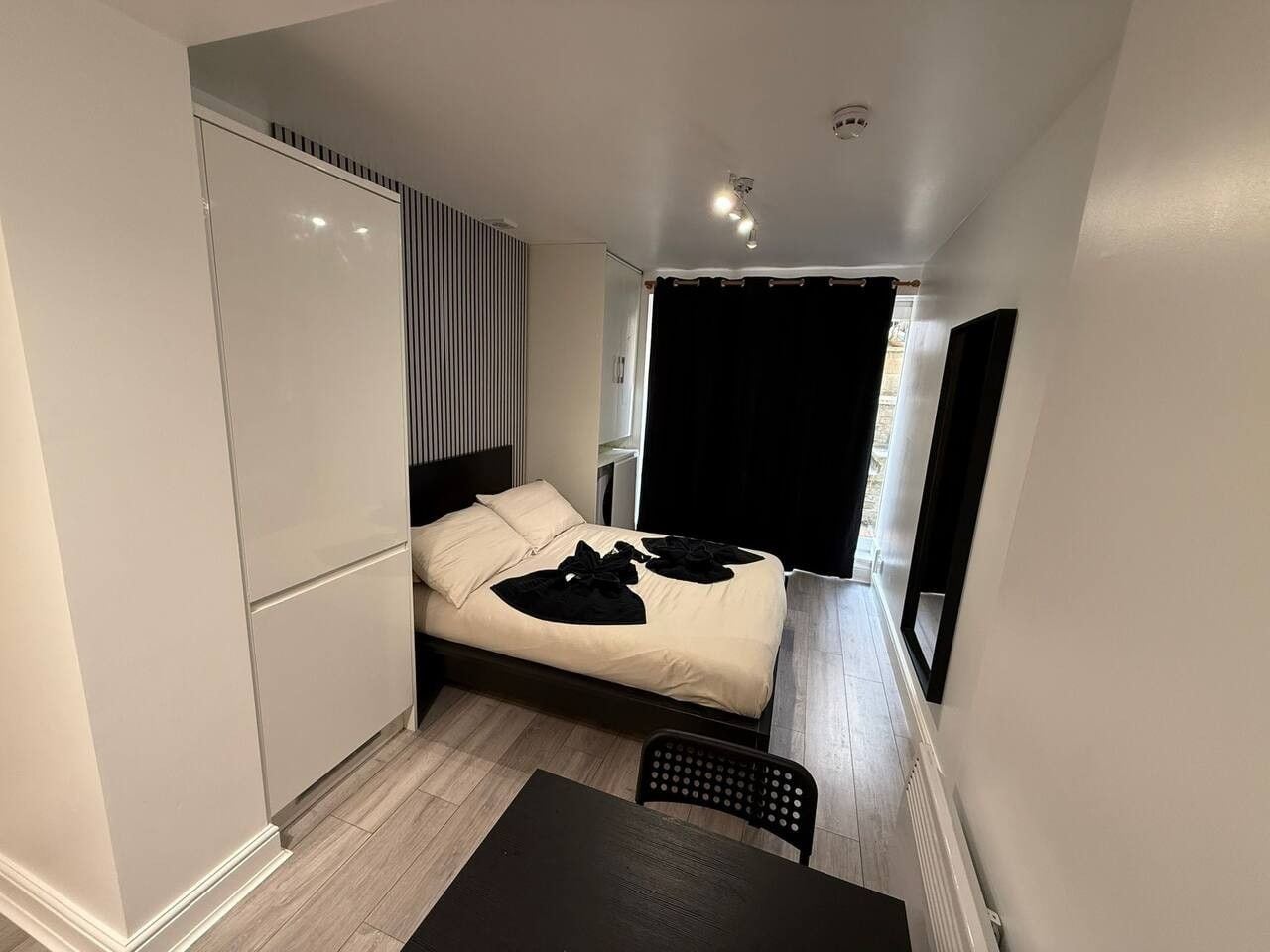 Una habitación pequeña con cama, una silla y una mesita.