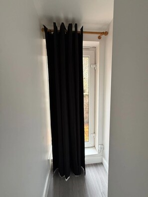 A room with a black curtain, a white door, and a window.