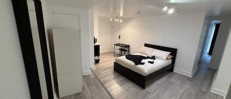 A modern bedroom with a large bed, a desk, and a chair.