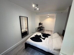 A modern bedroom with a bed, a desk, and a chair.