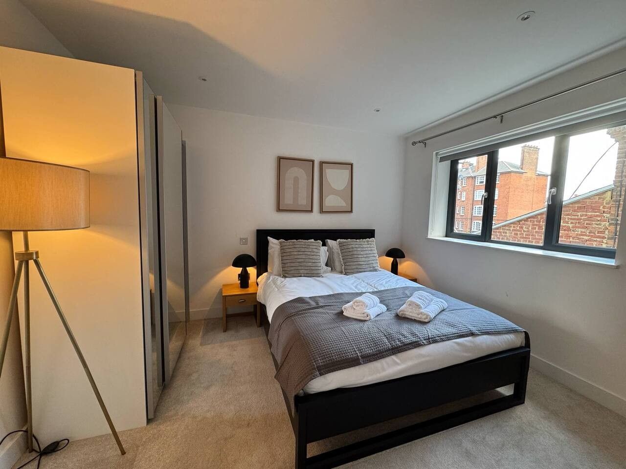 A bedroom with a bed, bedside lamps, a window, and a floor lamp.