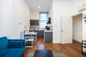 A compact living space with a kitchenette, a dining area, and a sofa. - Earl`s Court Residence | Elegant 1BR | London (Greater London)