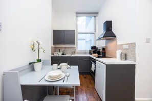 Eine kleine Küche mit Essbereich, einem Fenster und einer schwarzen Dunstabzugshaube.